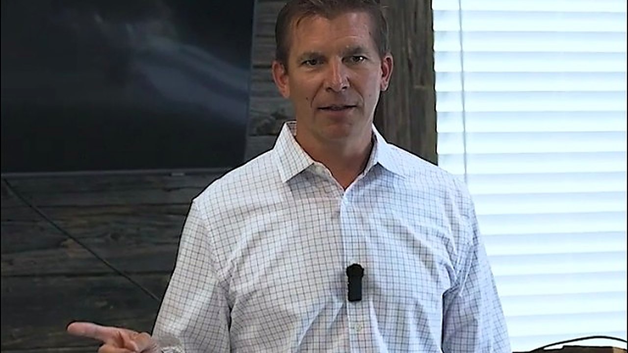 Brian Manhart speaking to a room, mid-sentence, gesturing with one hand.